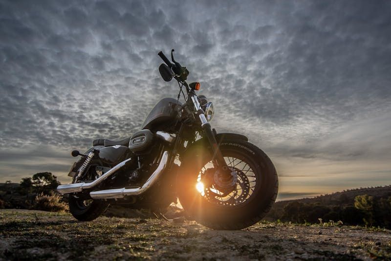 Motorrad im Gegenlicht der tiefstehenden Sonne unter bewölktem Himmel